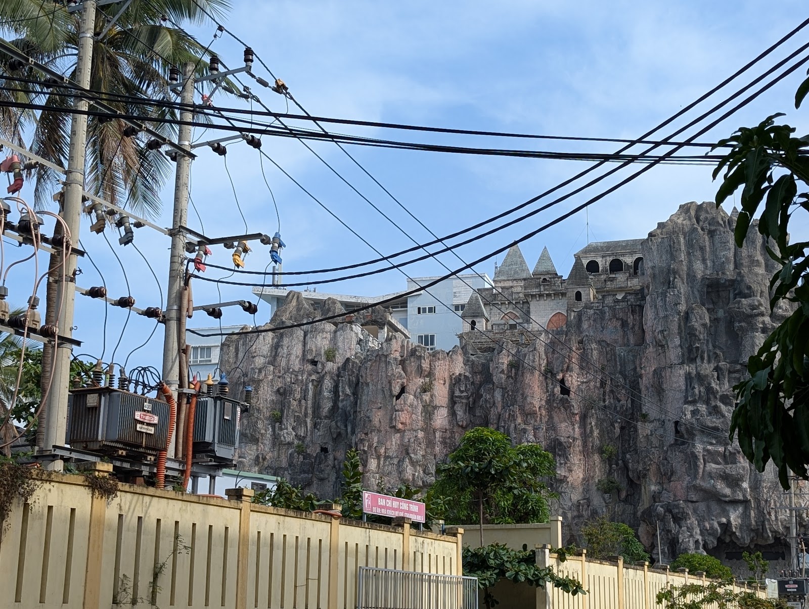 Photo of some power cables in the forground, with a building in the
                 background that looks like a castle on top of a chunk
                 of artificial rock