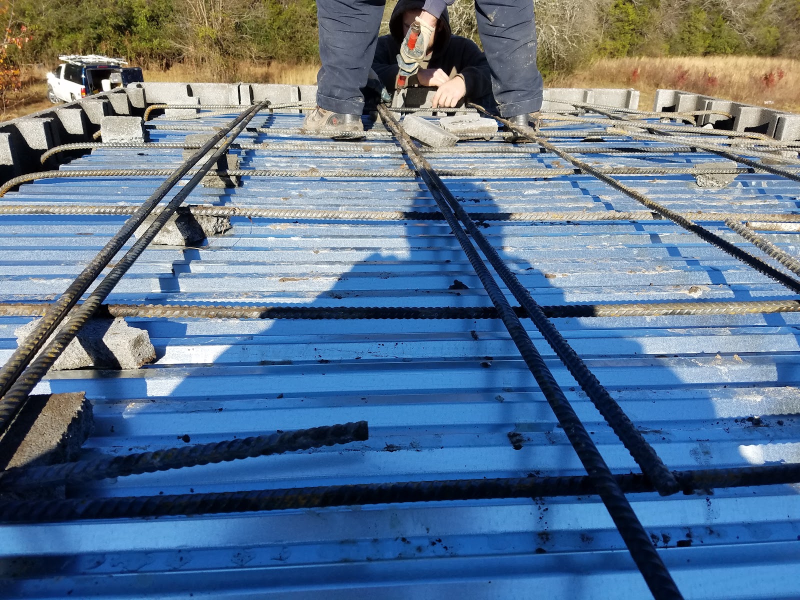 A rebar grid is laid over a corrugated metal deck for the roof of a storm shelter during construction.