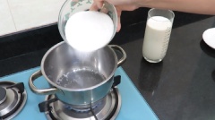 Khi nước sôi thì cho 250g đường vào, đun cho tan hết. Thoa ít bơ lên 1 vòng trong thành nồi để sữa không bị trào khỏi nồi khi đun.