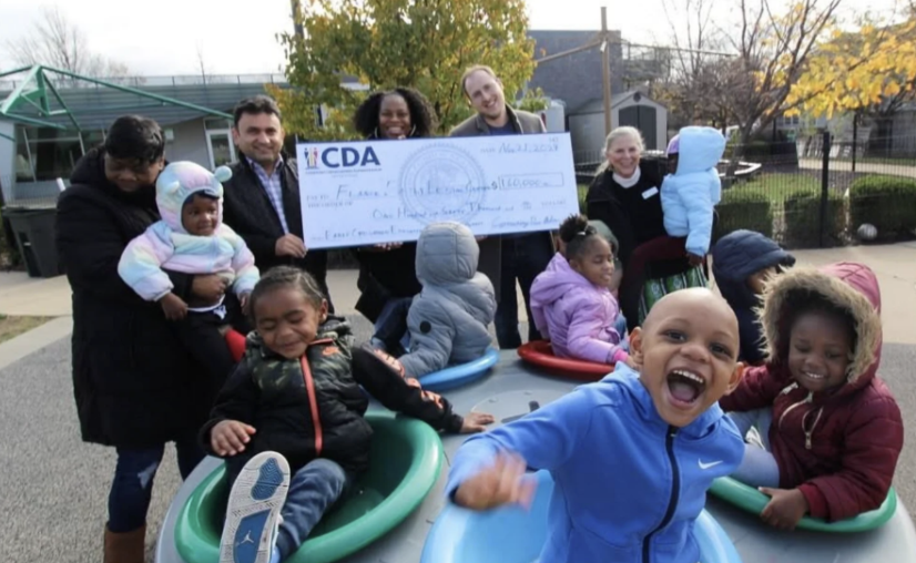 Nahuel Fefer presenting a grant to an early childcare center, children playing in the foreground.