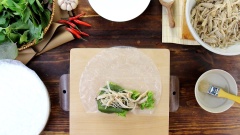 Trải bánh tráng ra mặt phẳng, phết nước để làm mềm mặt bánh, thêm vào rau tùy thích, da và thịt heo đã trộn thính rồi cuộn lại thành cuốn to. Làm tương tự cho đế hết nguyên liệu.