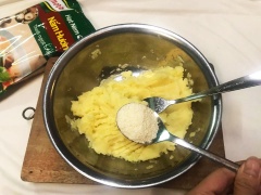 Cho vào khoai nghiền 1 muỗng canh hạt nêm nấm hương Knorr, 1/2 muỗng cà phê đường trắng. Dùng nĩa trộn đều. Cho 3 muỗng canh bột bắp vào. Trộn cho thật kĩ, thấy khoai tây dẻo mềm.