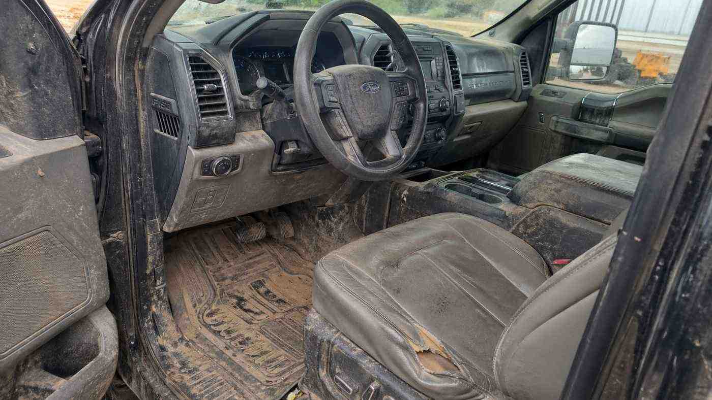 Dirty used F-150 interior with torn driver seat, muddy floor mats, and visible cab wear before protective upgrades.