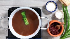 Sau khi đậu đỏ đã được hầm chín mềm, cho 200gr đường phèn và 5 lá dứa vào nấu lửa nhỏ thêm 30 phút nữa cho đậu ngấm đường.