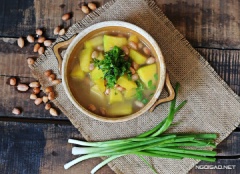 Khi bí và đậu phộng đã chín tắt bếp, cho canh ra tô rắc thêm hành lá và tiêu.