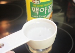Tiếp theo, cho mật bắp, đường trắng, 60ml nước lọc vào nồi, bắc lên bếp, khuấy đều để đường tan hết.