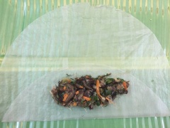 Cho bánh tráng ra mặt phẳng, gấp một mép bánh tráng rồi cho nhân vào. Gấp 2 đầu trước khi cuốn vì như vậy sẽ không bị cháy đầu nem khi chiên.