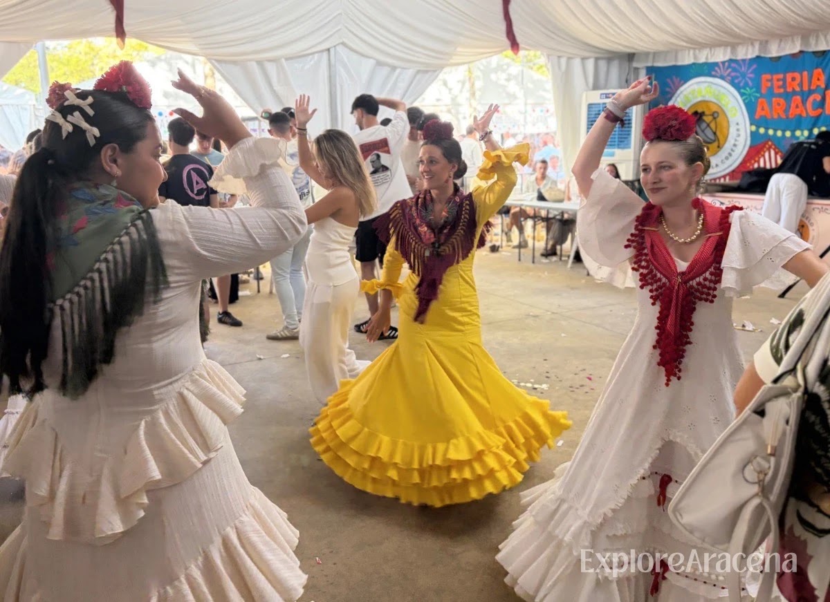Young women in feria dresses dancing sevillanas inside a caseta at the Feria de Aracena.