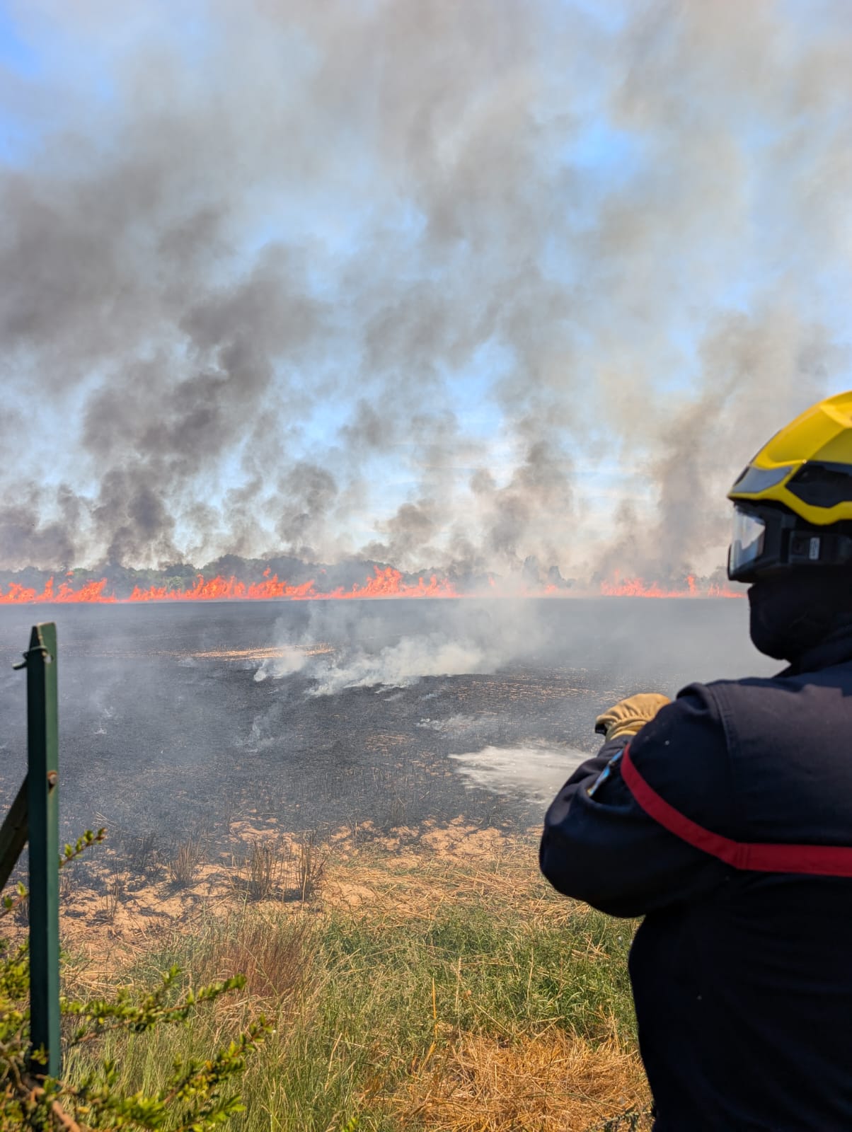 Un sapeur-pompier face à l'importante colonne de fumée dégagée par l'incendie