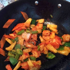 Đun nóng 2 muỗng canh dầu ăn, cho gà đã ướp vào chiên sơ qua. Đến khi gà cháy xém cạnh thì thêm vào ớt chuông xanh, cà rốt, 2 muỗng canh nước sốt cà chua vào đảo cùng. Cuối cùng thêm dứa, hạt nêm gà, đường vào nêm nếm cho vừa ăn thì tắt bếp. Cho thêm hành lá cắt nhỏ vào chảo, đảo đều rồi tắt bếp.