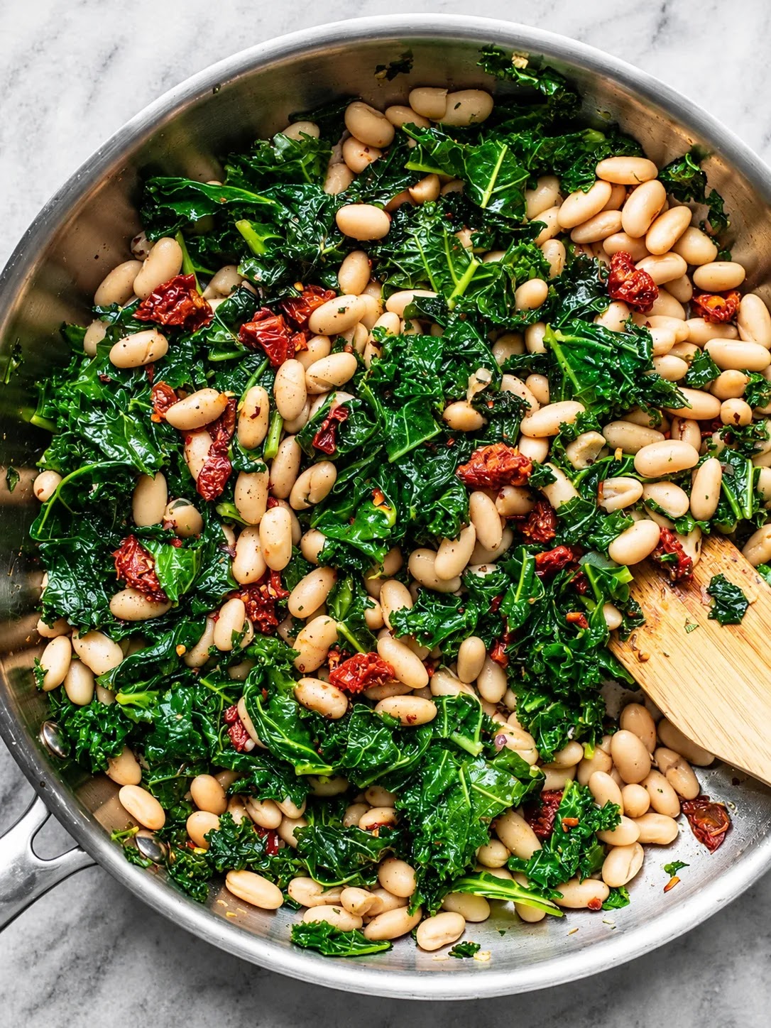 Creamy skillet filled with white cannellini beans, wilted kale, and sun-dried tomatoes