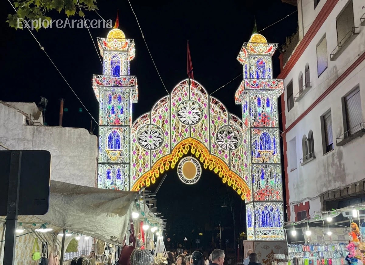 Illuminated portada marking the entrance to the Feria de Aracena at night.