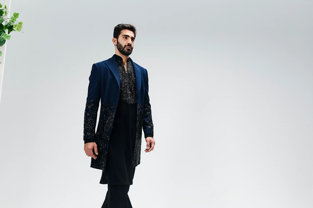 Man in a navy blue beaded long jacket layered over a black kurta and trousers