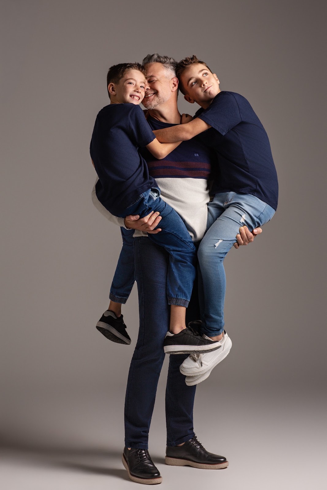 Pai segurando os filhos no colo em imagem descontra�da para campanha Dia dos Pais.