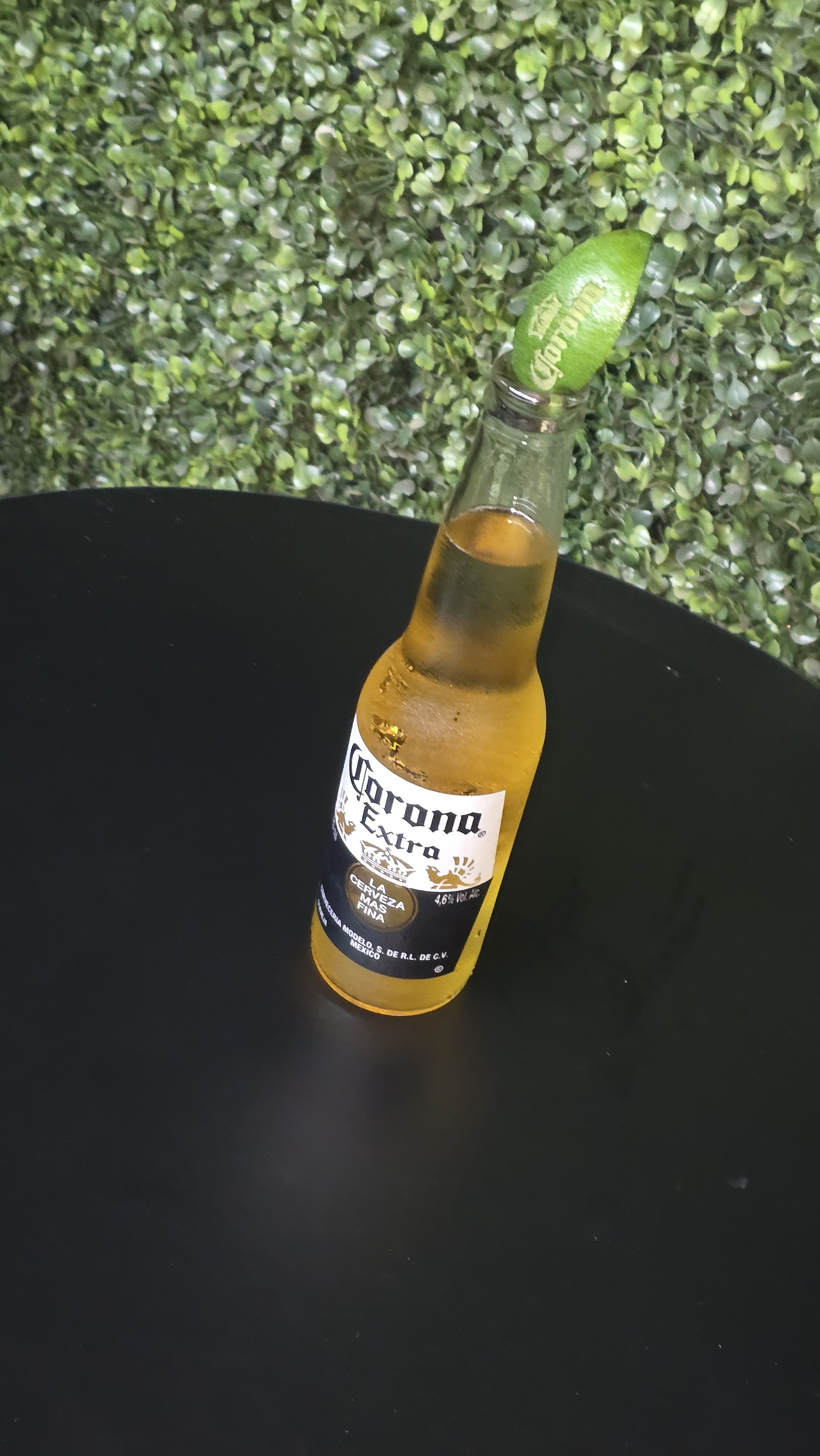 Vista em ângulo da garrafa de Corona com o limão gravado a laser, destacando a marca na fruta e no rótulo.