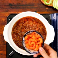 Cho tiếp, 50gr tôm khô đã ngâm mềm với 40gr ớt hiểm và 30gr tiêu xanh vào kho thêm vài phút thì tắt bếp, rắc hạt tiêu lên trên.