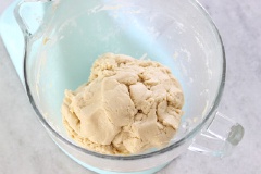 Bật máy đánh đều tất cả. Trong một cái bát khác, bạn trộn đều bột, muối nở, muối với nhau, rồi cho vào chung với hỗn hợp trứng bên trên, nhào đều.