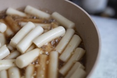 Nêm Tteok với 3 muỗng cà phê đường, 1 muỗng canh nước tương, 2 muỗng cà phê dầu mè rồi đảo đều tay cho thấm gia vị. Vẫn để lửa lớn và nấu sôi.