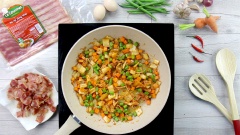 Trên chảo lúc nãy chiên thịt xông khói, bạn cho tỏi băm vào phi vàng thơm. Sau đó cho cà rốt, đậu que và kim chi vào, xào cho các loại rau củ vừa chín tới.