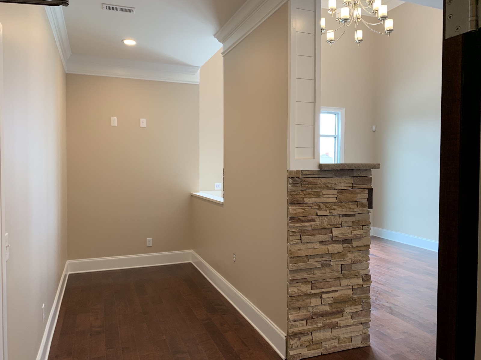 Interior view of a health clinic with hardwood floors, beige walls, and a partition wall featuring stacked stone and white paneling.