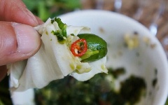 Xé miếng bắp cải vừa ăn, bổ đôi quả nhót, kẹp vào giữa một miếng lá tỏi, sau đó thêm gừng, ngò rí, cuộn lại cho thật khéo là xong. Món này chấm cùng nước chẳm chéo ngon hết sảy.