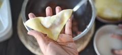 Khi nhân đã thấm gia vị xong, lấy một miếng vỏ hoành thánh đặt lên tay rồi múc 1 muỗng nhân cho vào chính giữa, thoa một ít nước xung quanh rìa vỏ để tạo kết dính. Gấp vỏ lại thành hình tam giác sau đó bẻ hai đầu lại với nhau, dính bằng nước.