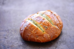 Bánh mì bạn chọn loại đặc ruột nhé. Dùng dao rạch ổ bánh mì thành hình caro như hình nhưng không đứt rời ra, vỏ phía dưới bánh mì vẫn còn nguyên. Cho bơ, bột tỏi, lá oregano vào bát, cho vào lò vi sóng đun chảy.