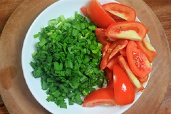 Hẹ rửa sạch cắt nhỏ, cà chua rửa sạch cắt múi cau. Trứng đập vào chén đánh tan.