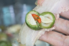Trải thịt ba chit ra, cho sấu, ớt, tỏi vào đầu miếng thịt ba chỉ, cuốn tròn thịt lại là được.