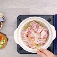 Phi vàng 10gr tỏi băm, vớt ra để riêng. Tiếp theo, cho 20gr sả băm và 200gr thịt ba chỉ cắt mỏng vào xào cho săn lại.