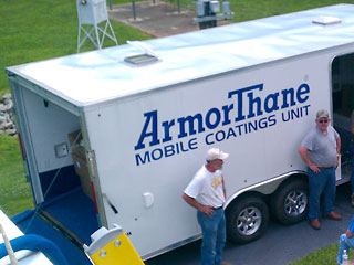 White mobile coatings trailer with two applicators standing beside it