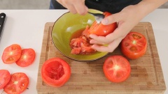 Rửa cà chua, cắt đôi quả cà chua phần sát cuống, sau đó múc bỏ ruột cà chua ra. Để sang một bên. Hành lá băm nhỏ, hành khô băm nhỏ, tỏi băm nhuyễn, hương thảo thái nhỏ, phần ruột cà chua dầm nát.
