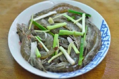 Rải đều gừng và hành lá vừa thái lên trên tôm đã ướp. Đặt bát tôm vào hấp khoảng 8 phút là được.