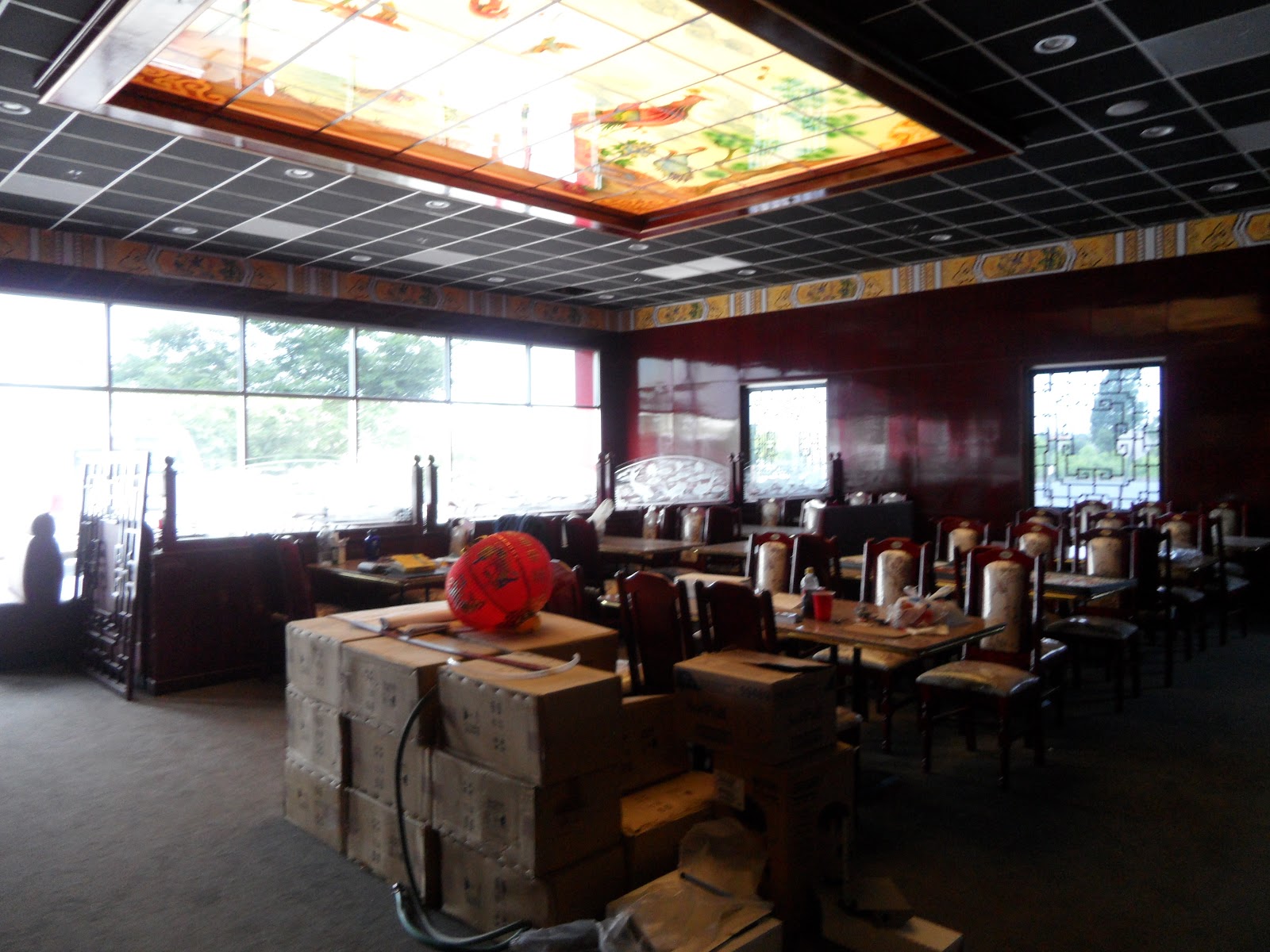 Interior view with stacks of boxes, tables and chairs, and a large decorative stained-glass style ceiling light fixture.