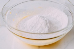 Dùng một chiếc rây để rây bột mì, bột bắp và bột nở cho mịn đều vào thau trộn trứng.