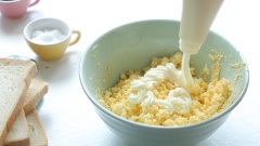 Dùng nĩa dằm nhuyễn trứng gà. Sau đó cho vào tô 50gr sốt mayonnaise, 1/4 muỗng cà phê muối và 1/4 muỗng cà phê tiêu. Tiếp tục dùng muỗng trộn đều cho trứng hòa quyện vào sốt.