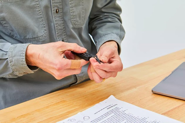 Close-up van een persoon die een Gerber Gear Dime Multi-Tool vasthoudt op een houten tafel