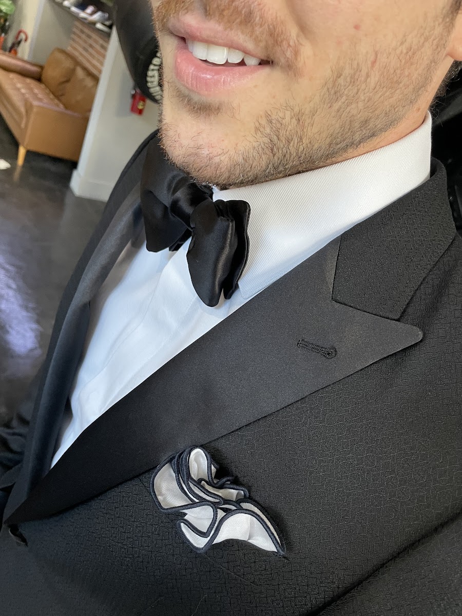 Close-up detail shot of black satin lapel facing on a formal tuxedo jacket showing the smooth light-catching surface