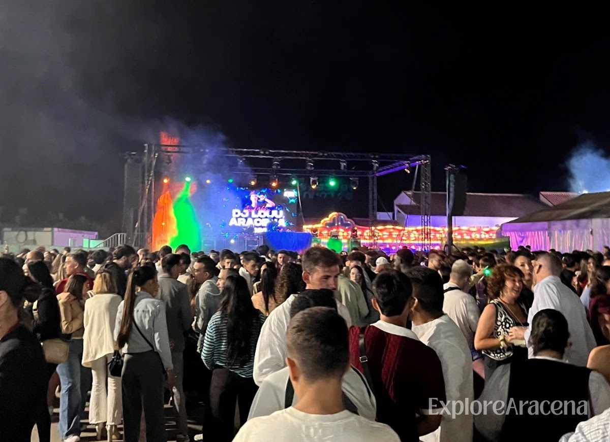 DJ performing on the Zona Joven stage before a large nighttime crowd at the Feria de Aracena.
