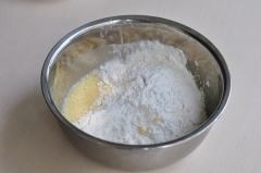 Đầu tiên, đập 2 quả trứng vào âu lớn, sau đó cho 20g bơ đã để mềm vào cùng 50g đường bột vào. Dùng phới lồng đánh cho trứng và các nguyên liệu khác hòa quyện vào nhau. Tiếp đó, rây 270g bột mì vào và trộn đều lên.