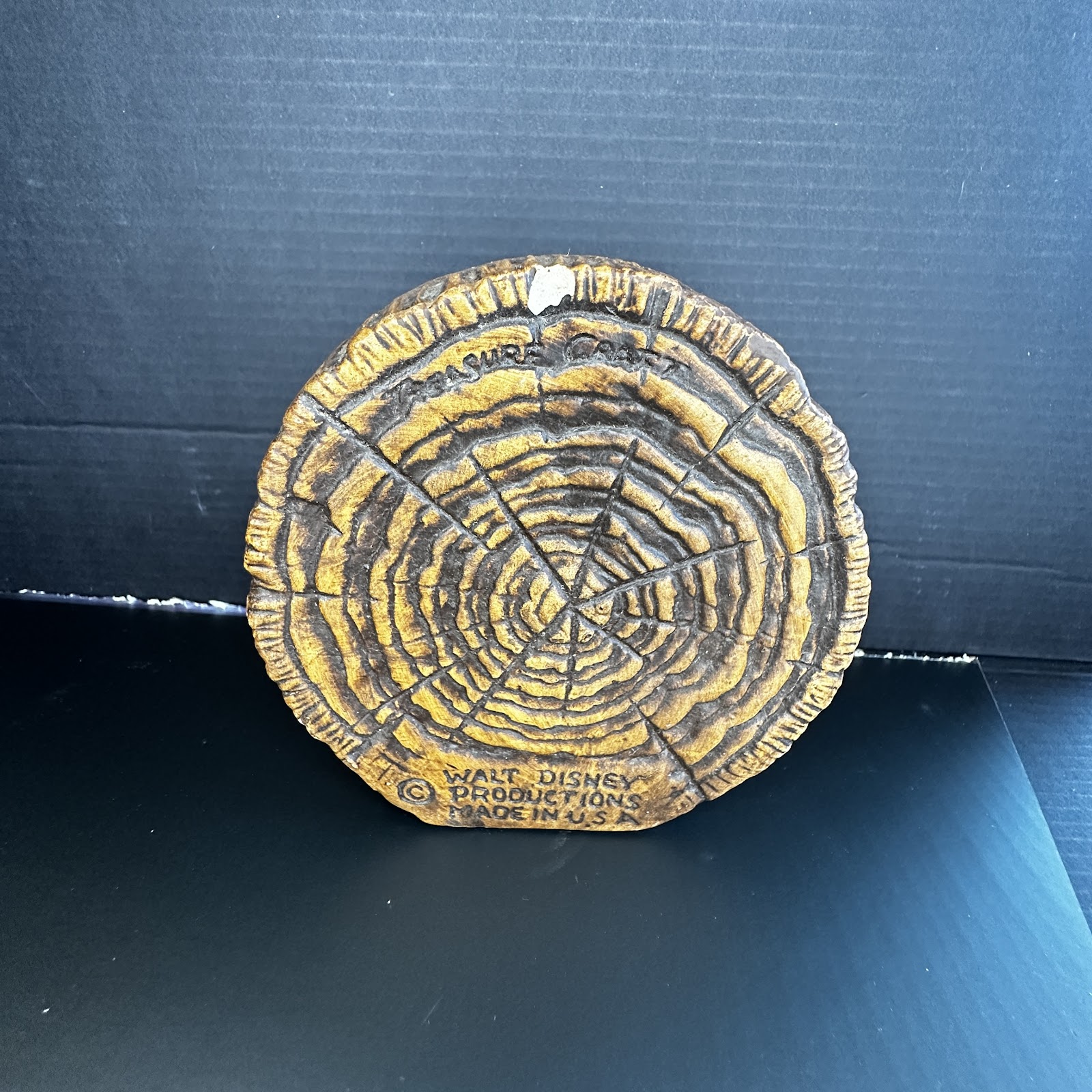 Treasure Craft ceramic log cross-section base with molded growth rings and bark edge texture, brown and tan wood-grain glaze, Walt Disney Productions marking on reverse