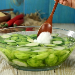 Đầu tiên, 1 kg cóc bao tử gọt sạch vỏ, chẻ đôi rồi ngâm nước lạnh thêm 1 muỗng canh muối hột để cho cóc cứng giòn hơn.