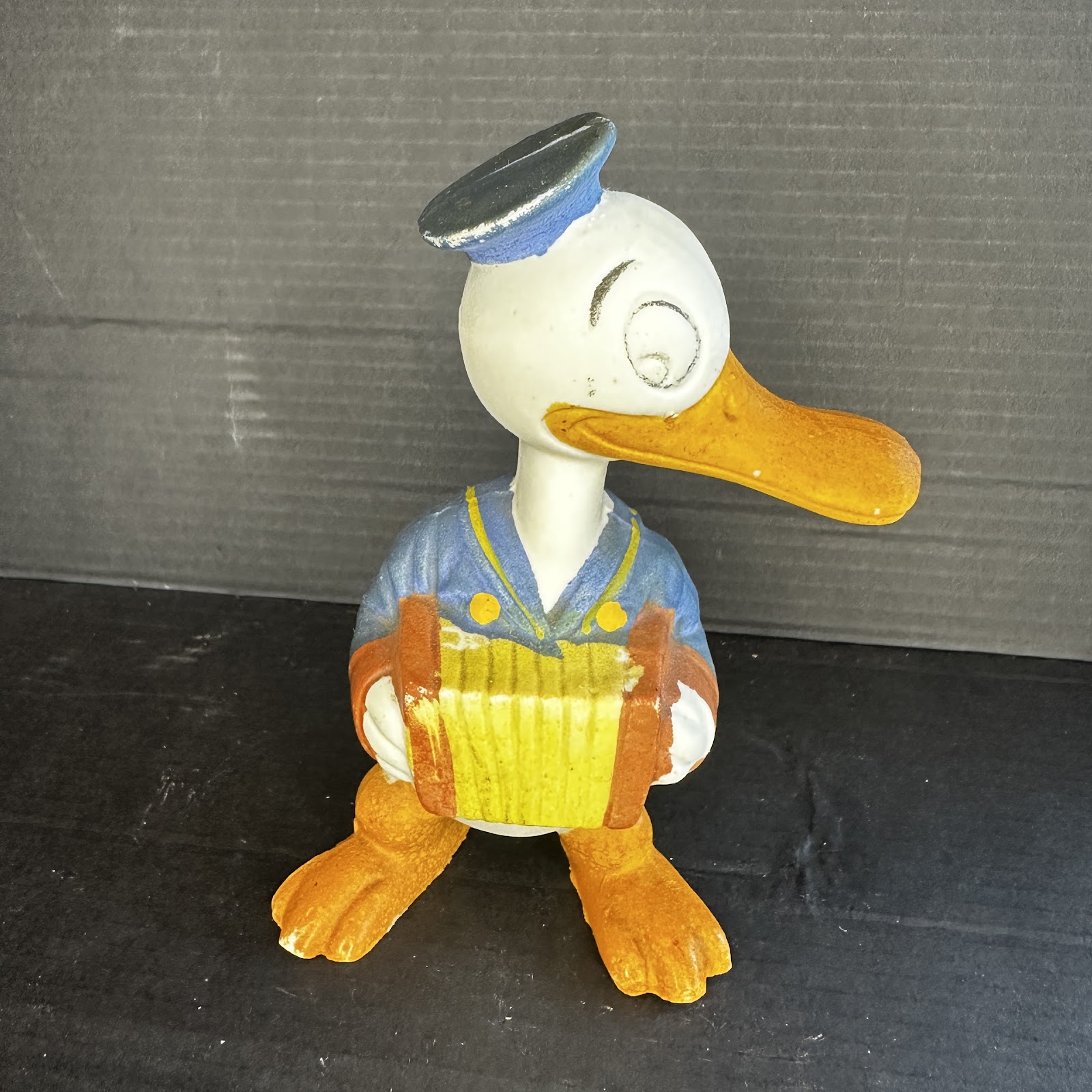 Vintage 1940s–1950s Donald Duck chalkware or composition figurine shown playing an accordion, painted in classic sailor-suit colors with age-appropriate surface wear
