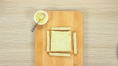 Tiếp đến bạn chuẩn bị cắt viền sandwich, dùng chài cán bột để cán mỏng bánh. Sau khi cán xong, bạn quết sữa đặc hoặc sữa tươi quanh 3 mép bánh. Sau đó gấp đôi bánh lại và dùng nĩa ấn cố định 2 mép bánh lại, bạn nhớ ấn cả 2 bên mặt. Sữa giúp 2 mép bánh dính lại với nhau hơn. Bỏ qua bước này thành phẩm bánh sẽ không dẻ mịn và khi bơm hỗn hợp sữa chua phô mai vào vỏ bánh xốp sẽ không giữ được nhân bên trong. Bạn lưu ý nhé.