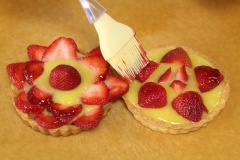 Sau đó, đổ phần hỗn hợp chanh trứng xuống đáy bánh tart. Xếp dâu tây lên trên rồi phết mứt lên dâu tây.