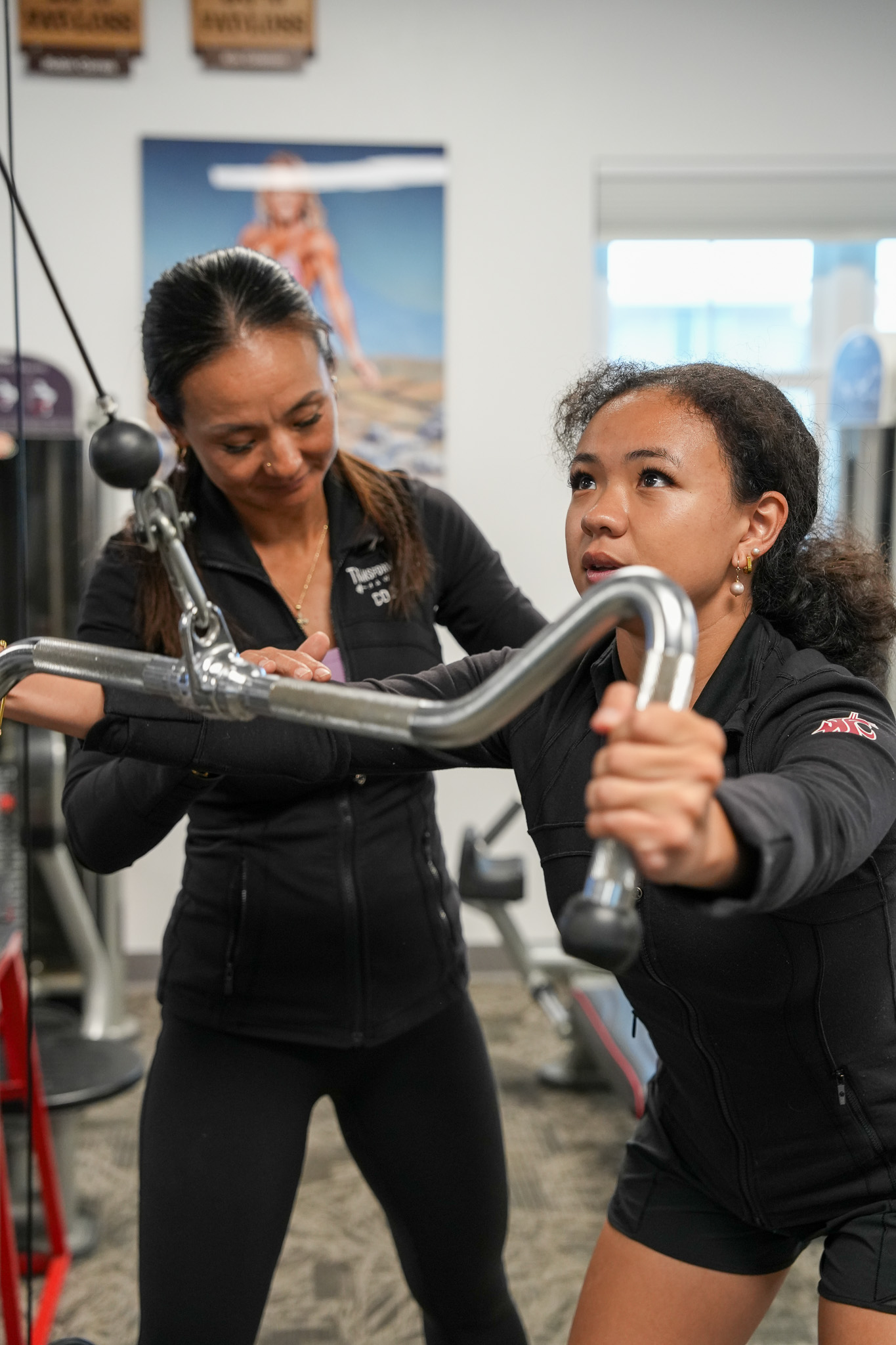 Coach spotting a teen on the cable machine