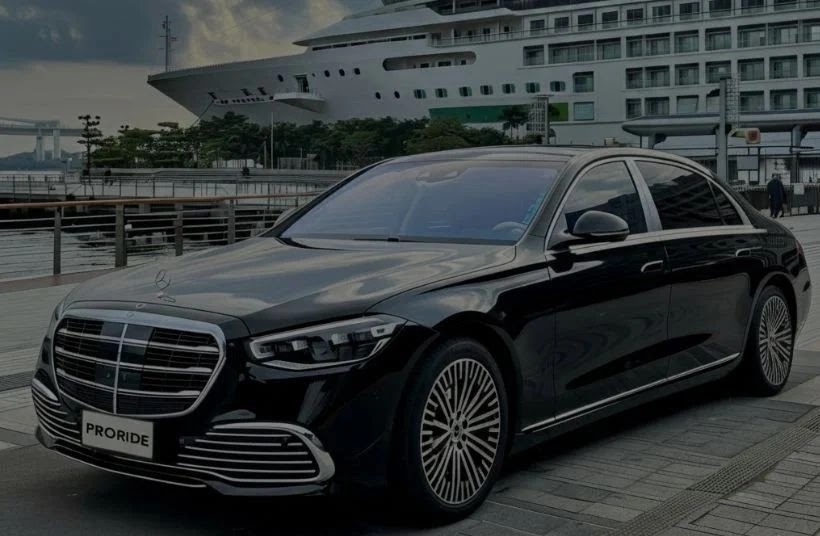 Black Mercedes-Benz sedan parked in front of a cruise ship at the port