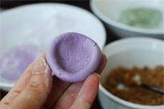 Chia bột đã ủ thành các phần nhỏ đều và vê tròn. Dùng ngón tay cái ấn vào giữa viên bột để tạo thành miệng giếng, rồi cho nhân mè vào. Gói kín phần bột để tạo bánh thành hình trăng khuyết. Làm tương tự đến hết nguyên liệu.