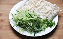 Dưa leo rửa sạch, gọt sơ vỏ, cắt sợi nhỏ. Cho mì udon ra đĩa. Hành lá rửa sạch, cắt nhỏ.