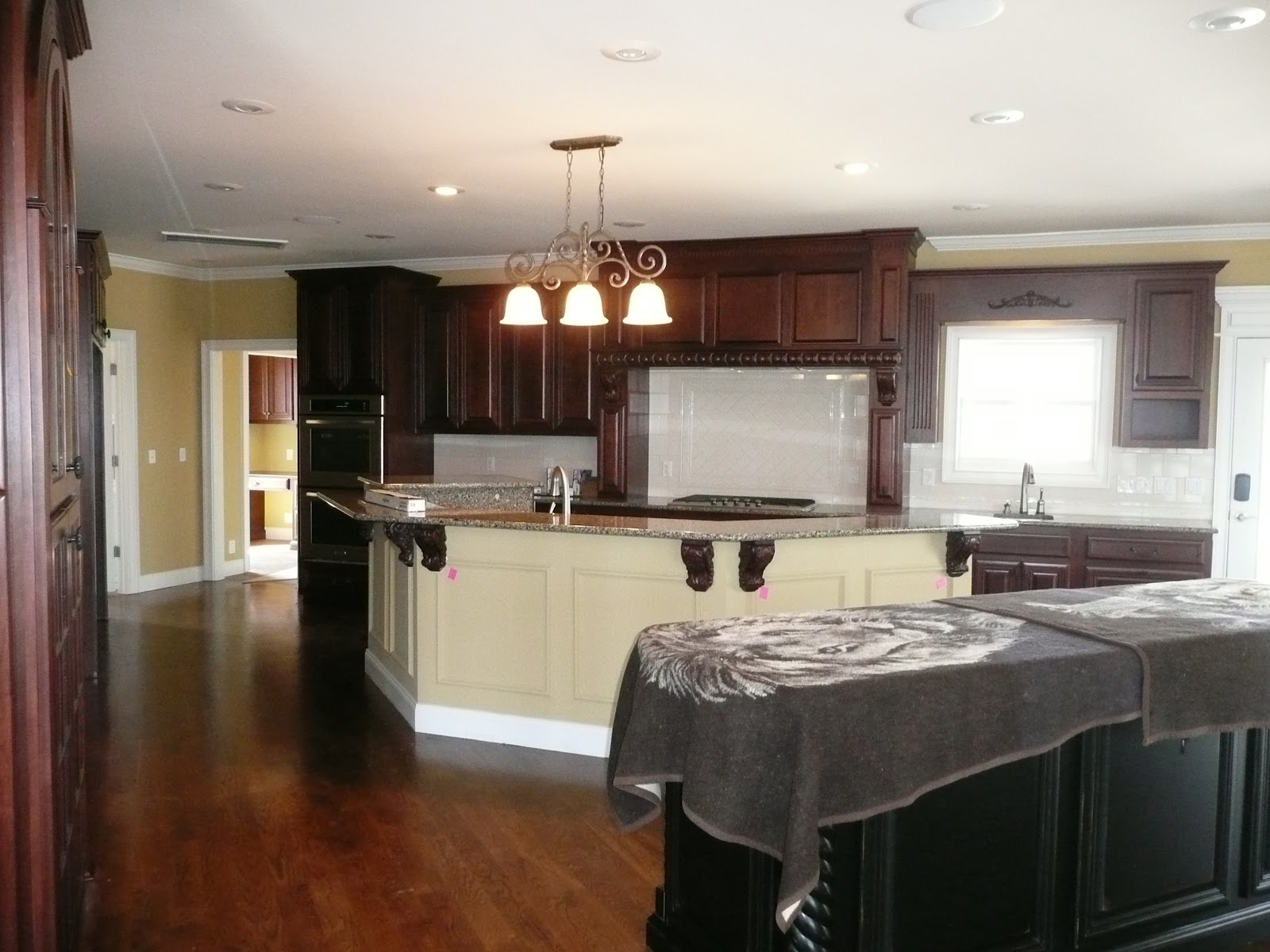 Kitchen interior featuring dark wood cabinetry, a large light-colored island with a granite countertop, and hardwood flooring.